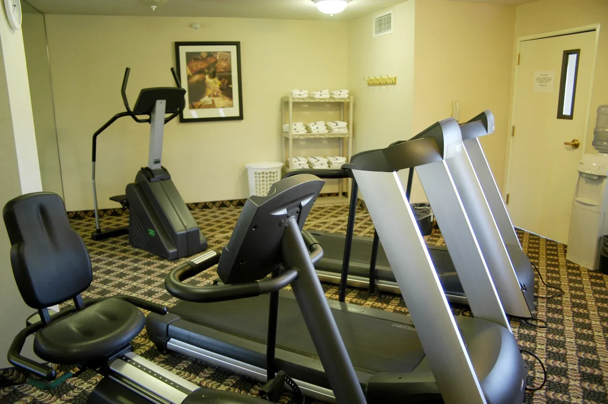 An inviting fitness center with treadmills, an elliptical machine, a water cooler, and an exercise mat, set in a bright, motivating space. The room supports both individual workouts and social interactions, underscoring the well-rounded amenities available.