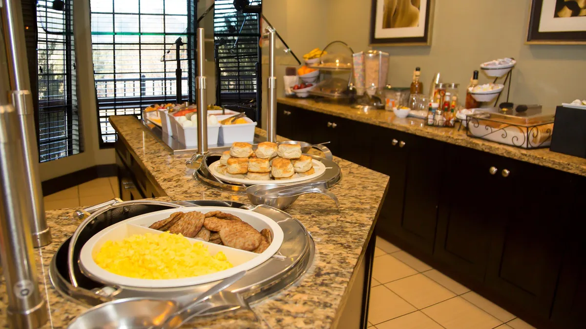 A bright breakfast buffet is arranged on a granite countertop, displaying a variety of freshly prepared food items. The cheerful setting encourages guests to start the day together, enjoying breakfast and making plans for shared adventures.